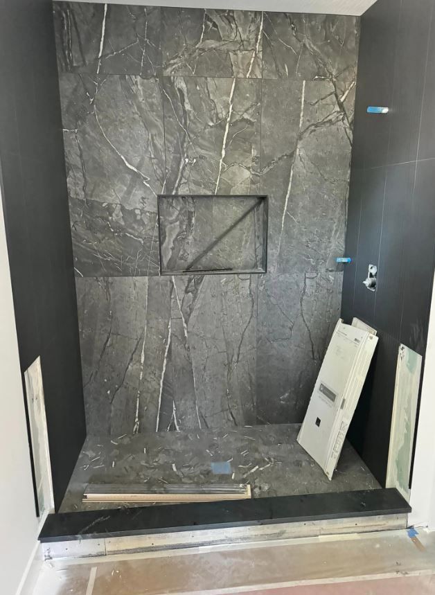 A bathroom with a black tiled wall and a shower stall