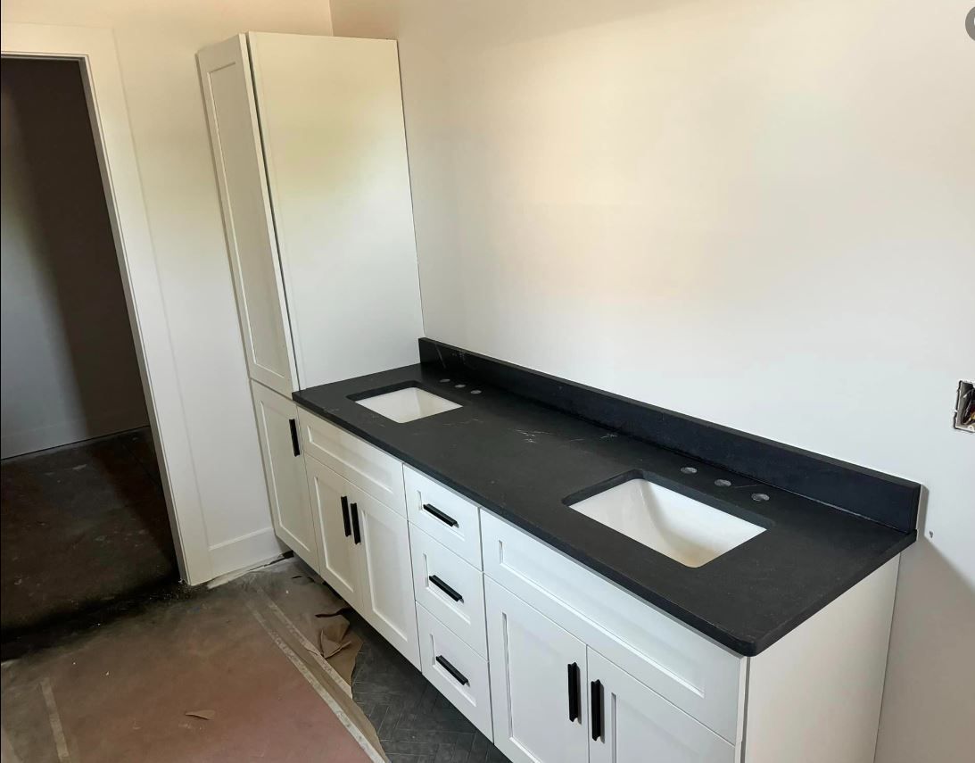 A bathroom with a black counter top and white cabinets