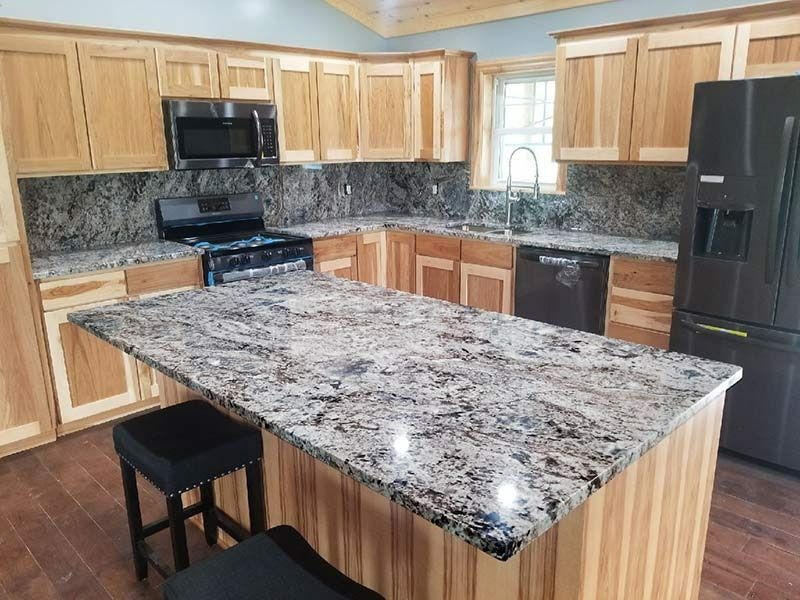 A kitchen with granite counter tops , stainless steel appliances , and wooden cabinets.