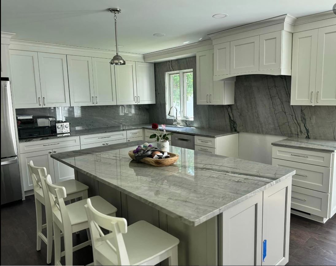 A kitchen with white cabinets, granite counter tops, and a large island