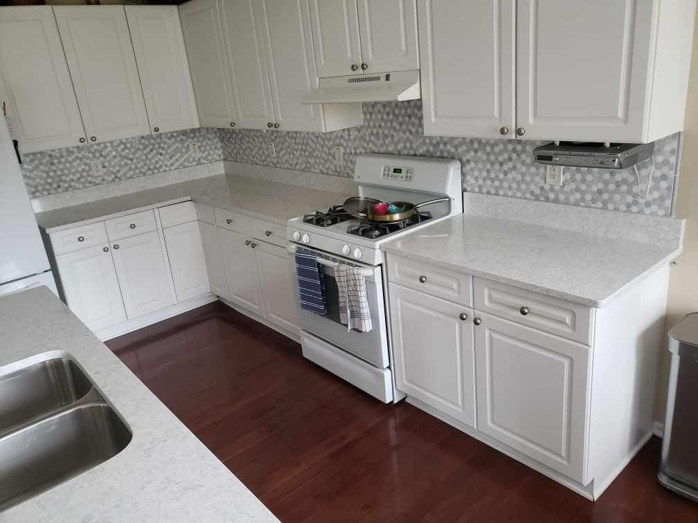 A kitchen with white cabinets , a stove and a sink.