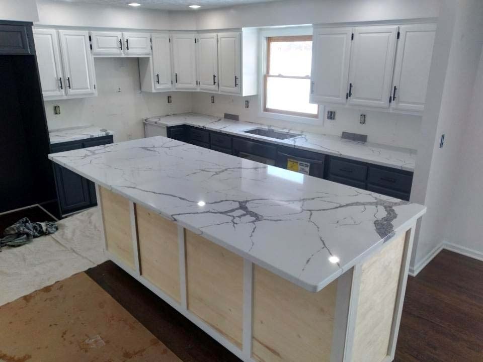 A kitchen with white cabinets and a large island in the middle.