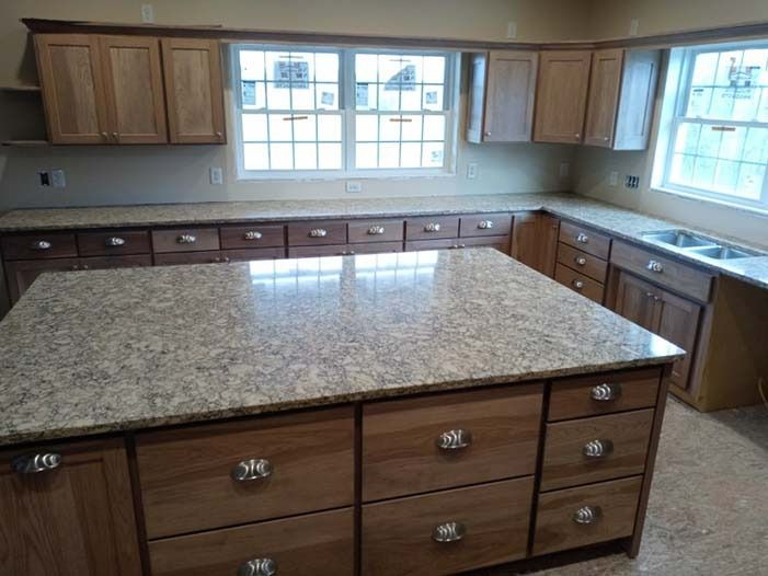 A kitchen with a large granite counter top and wooden cabinets.
