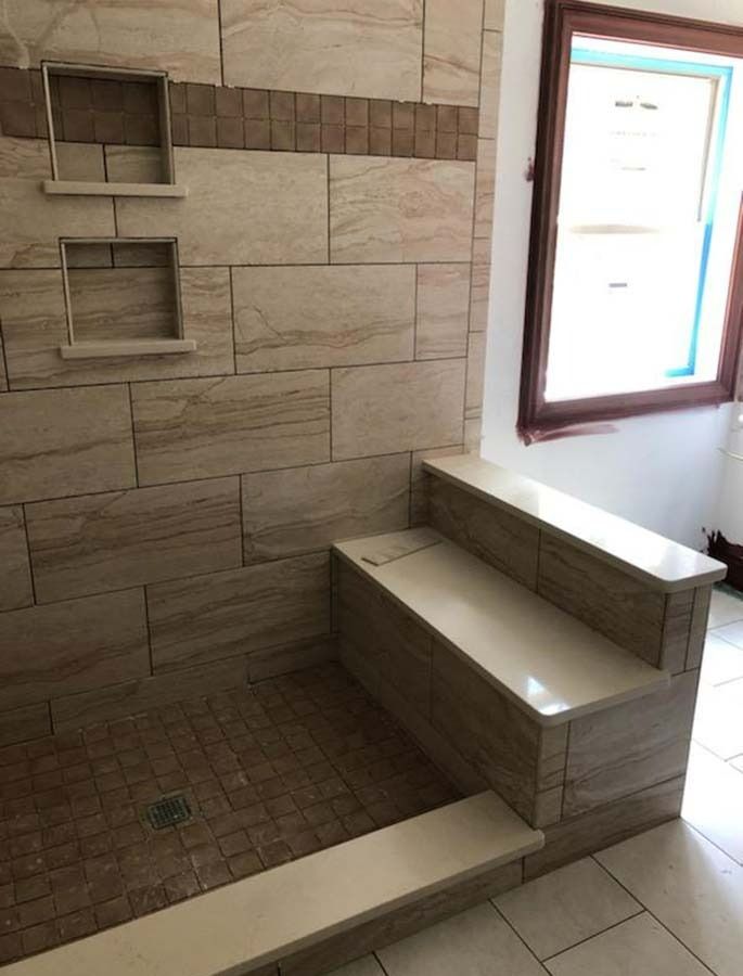 A bathroom with a walk in shower and a window.