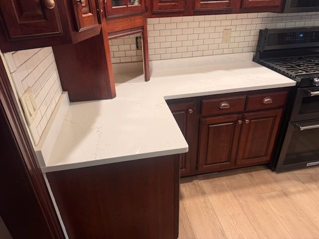 Kitchen with dark wood cabinets, white countertops, and subway tile backsplash.