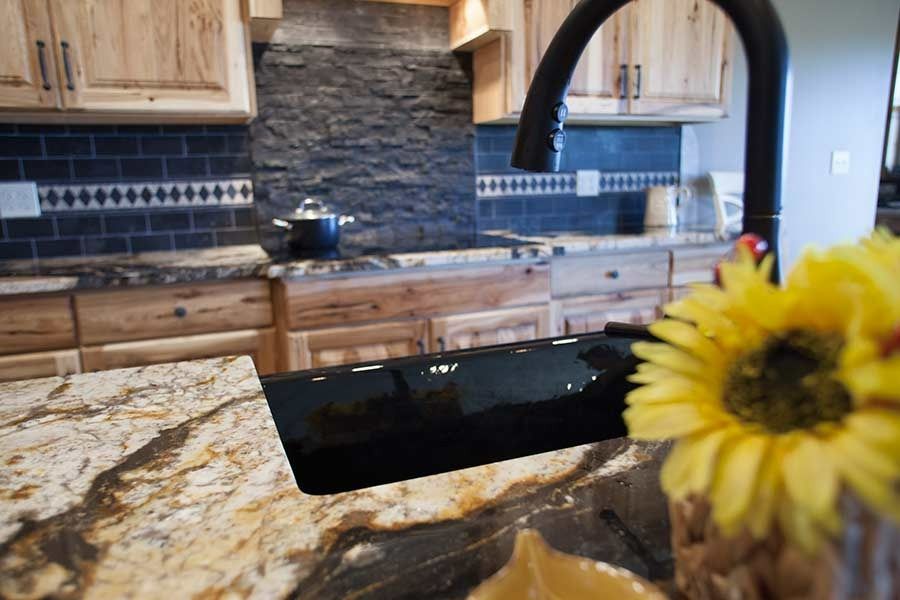 A kitchen with a black sink and a yellow flower on the counter.