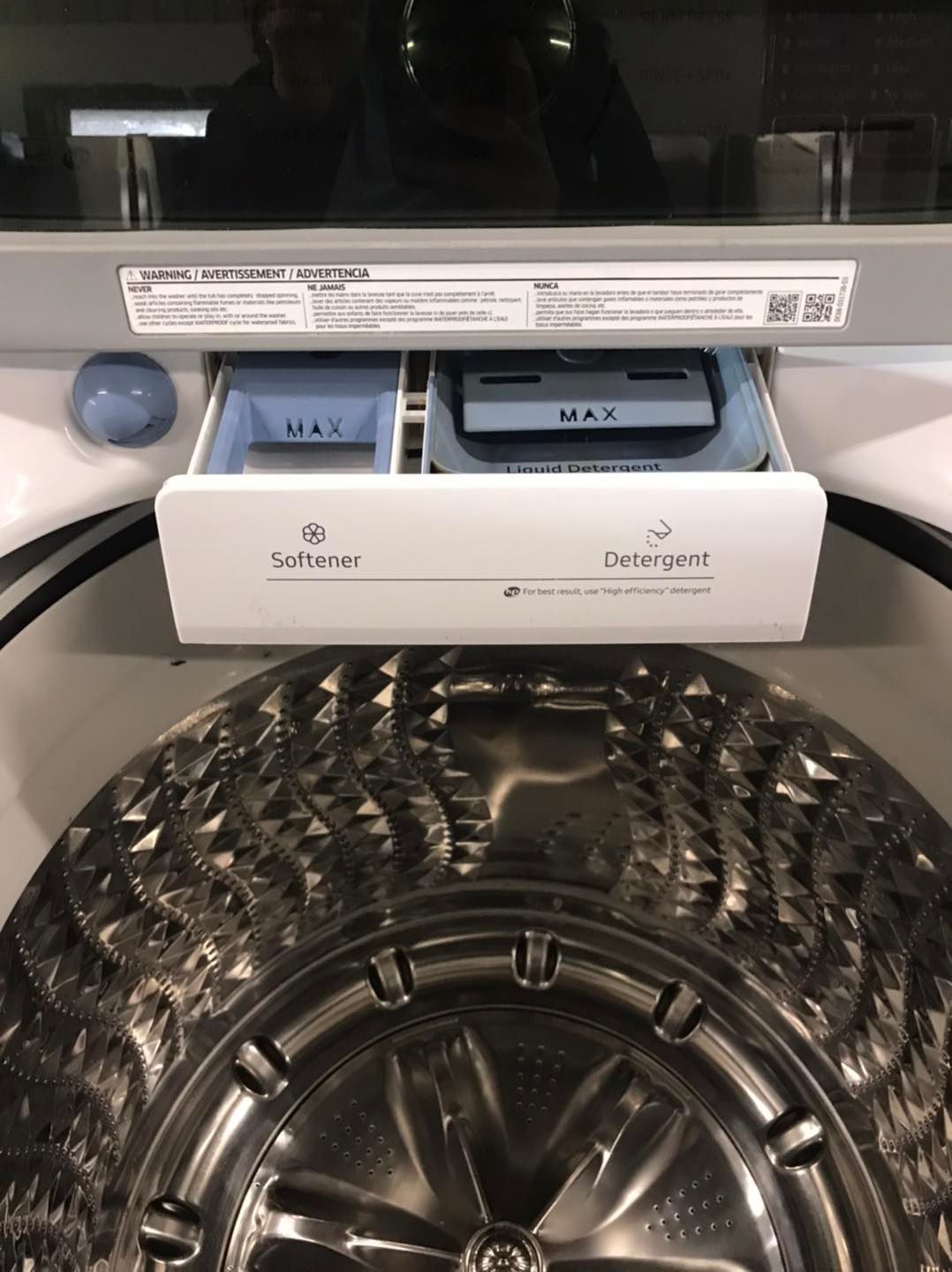 Open detergent dispenser on a washing machine with two compartments labeled 
