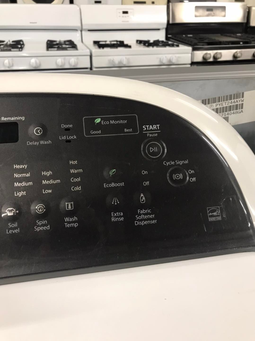 Close-up of a white washing machine control panel with various black buttons and a start button.