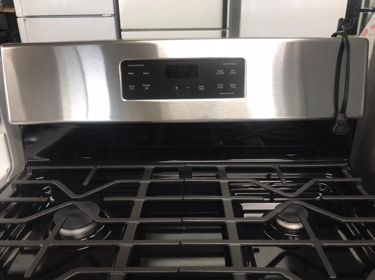 Gas stove with black grates and a stainless steel control panel displaying a digital clock.