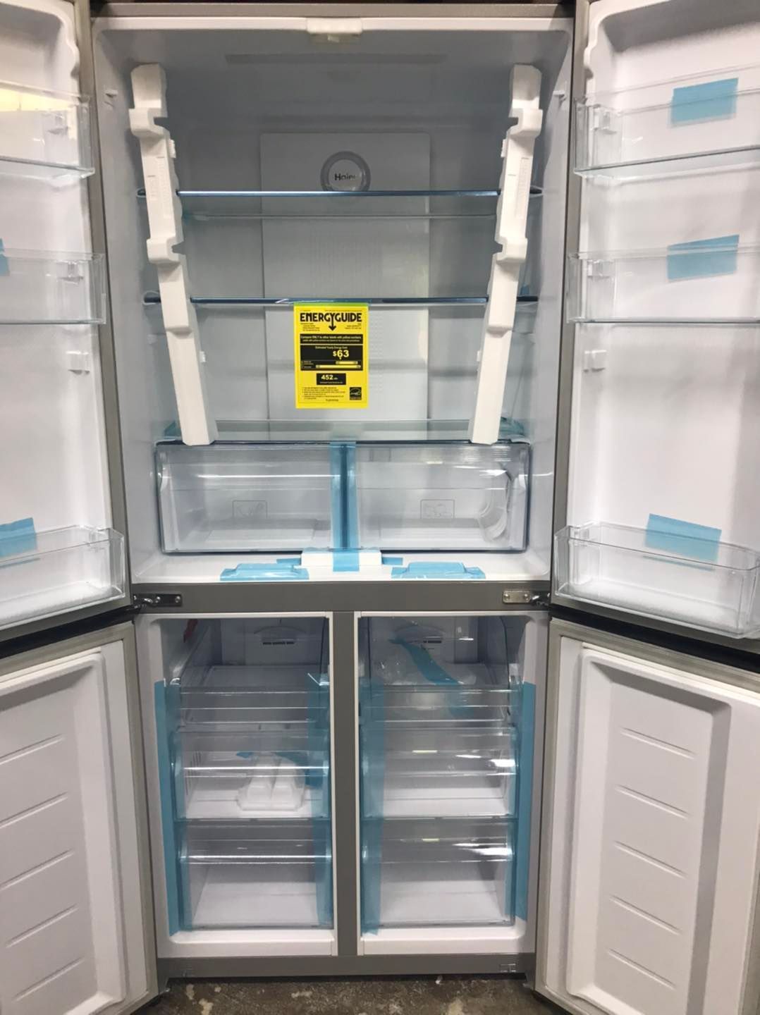 Open refrigerator showing empty shelves, drawers, and compartments.