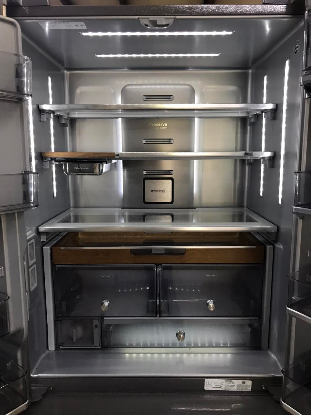 Interior of a stainless steel refrigerator with bright LED lighting and adjustable shelves.