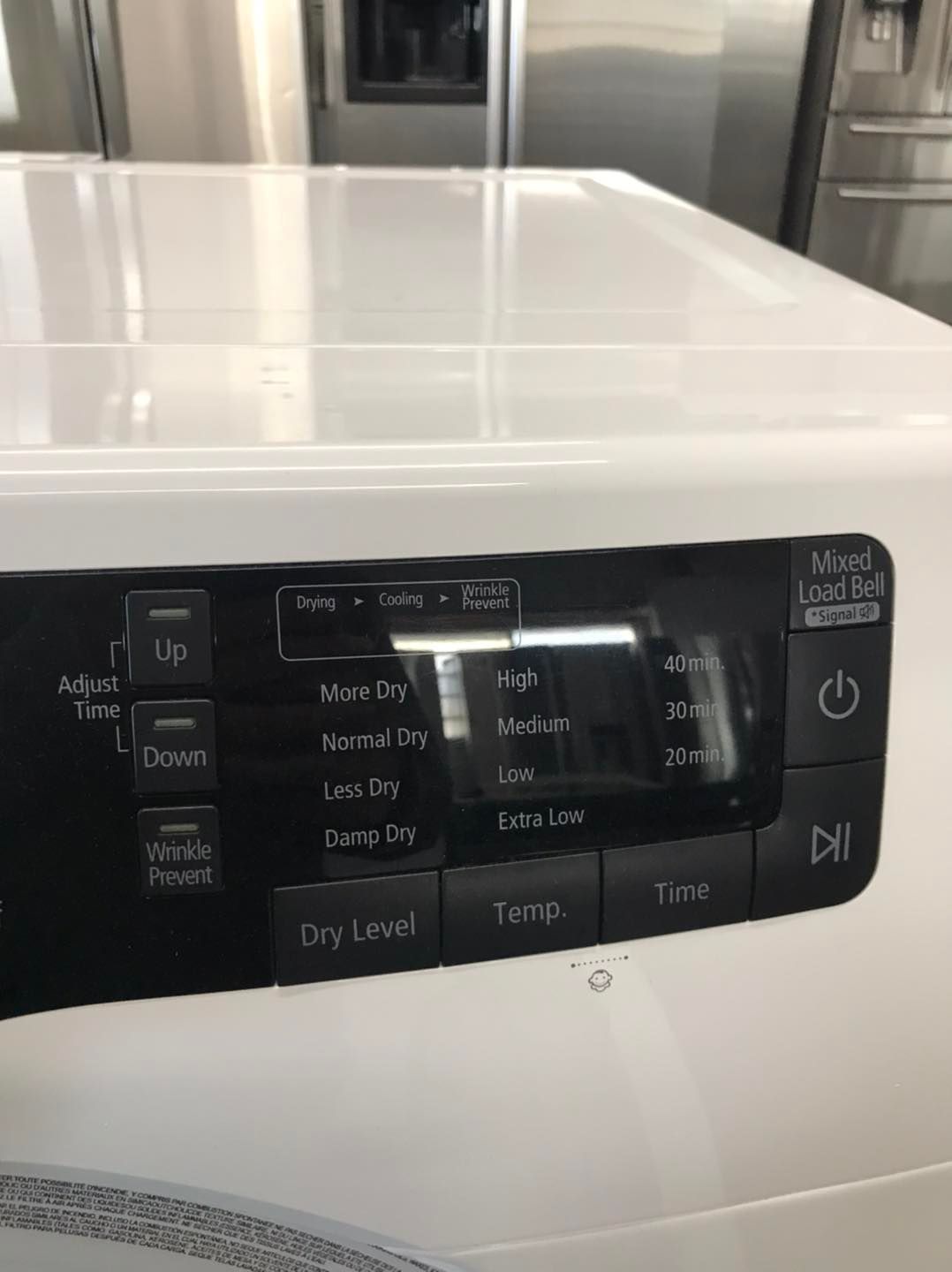 Close-up of a white dryer control panel with black buttons, and a digital display.