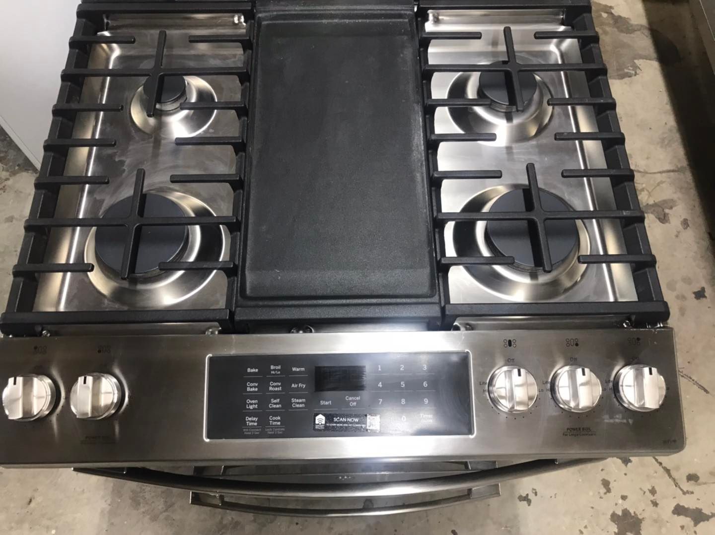 Stainless steel gas range with cooktop burners, griddle, and control panel.