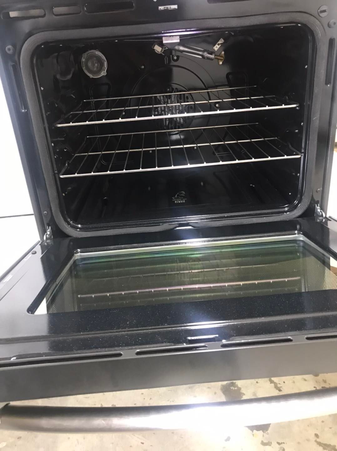 Open oven with racks inside. Black interior, glass door, stainless steel handle.