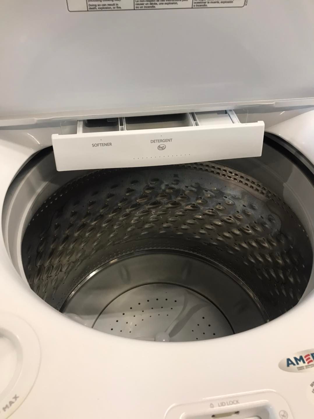 Top-load washing machine interior with open lid. Detergent dispenser at top.