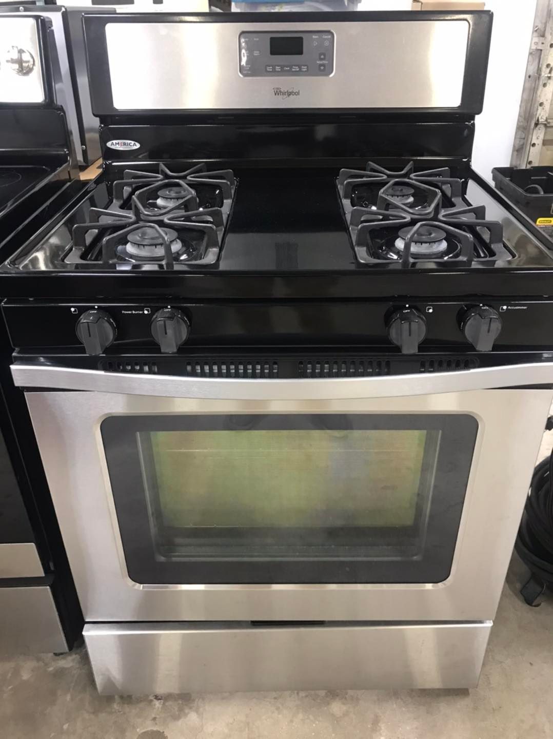 Stainless steel Whirlpool gas range with black cooktop, knobs, and oven window.