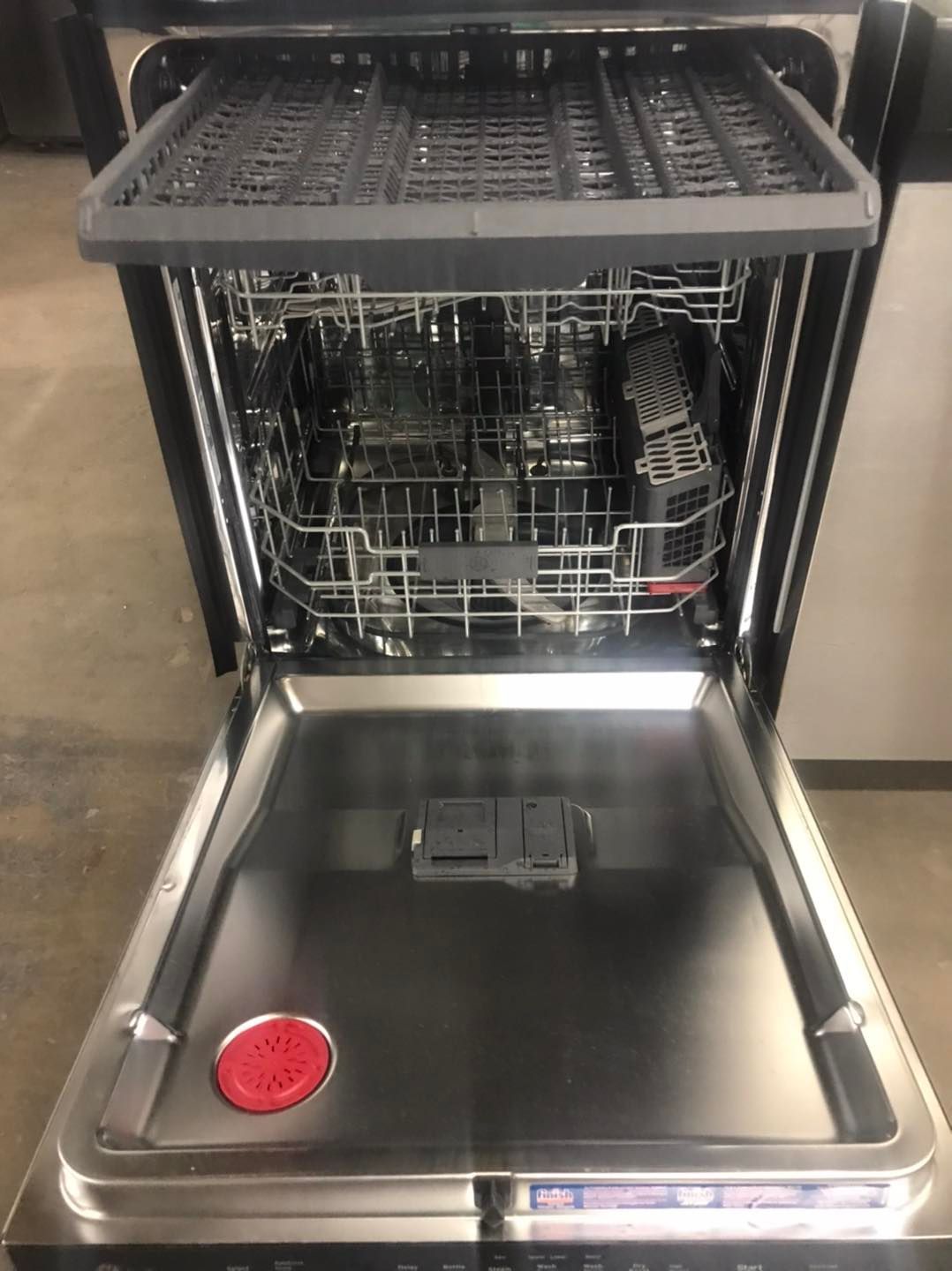 Open dishwasher, stainless steel interior, top rack, silverware basket, red filter.