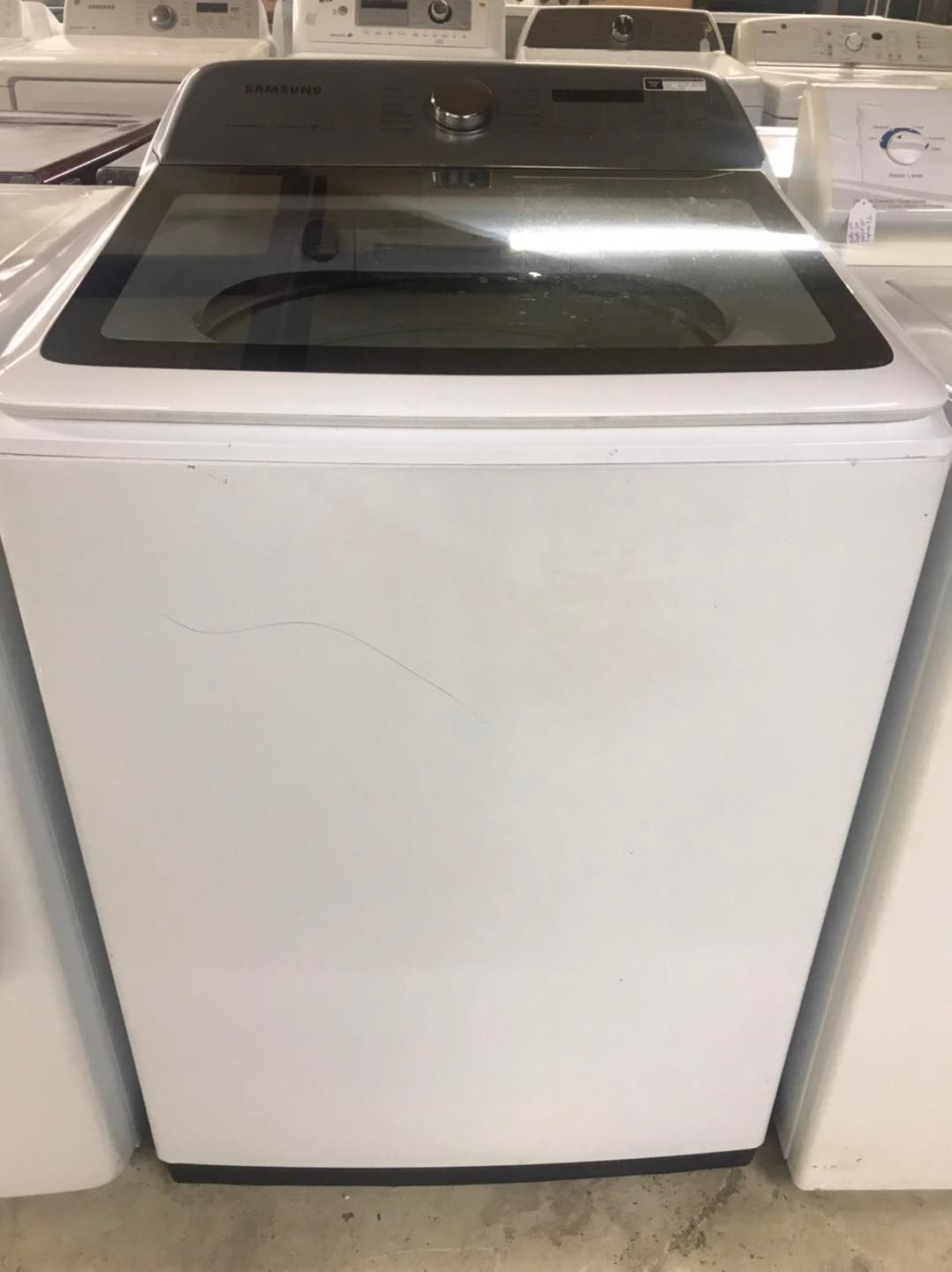 White top-load washing machine with a glass lid.