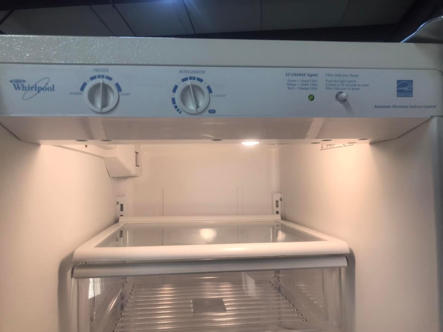 White Whirlpool refrigerator interior, controls on top, empty shelves.