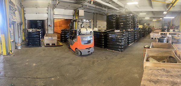 A forklift is driving through a large warehouse filled with lots of tires.