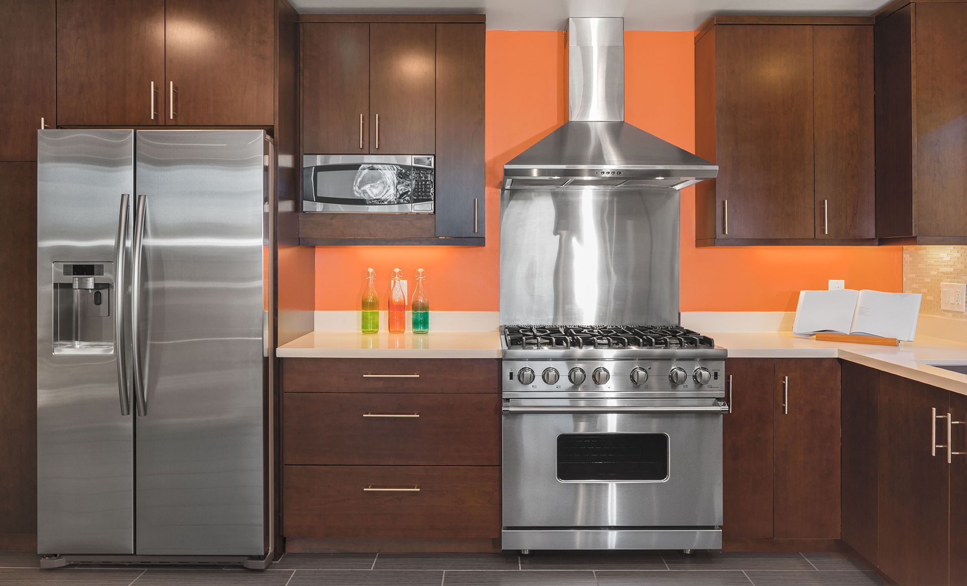 A kitchen with stainless steel appliances and orange walls