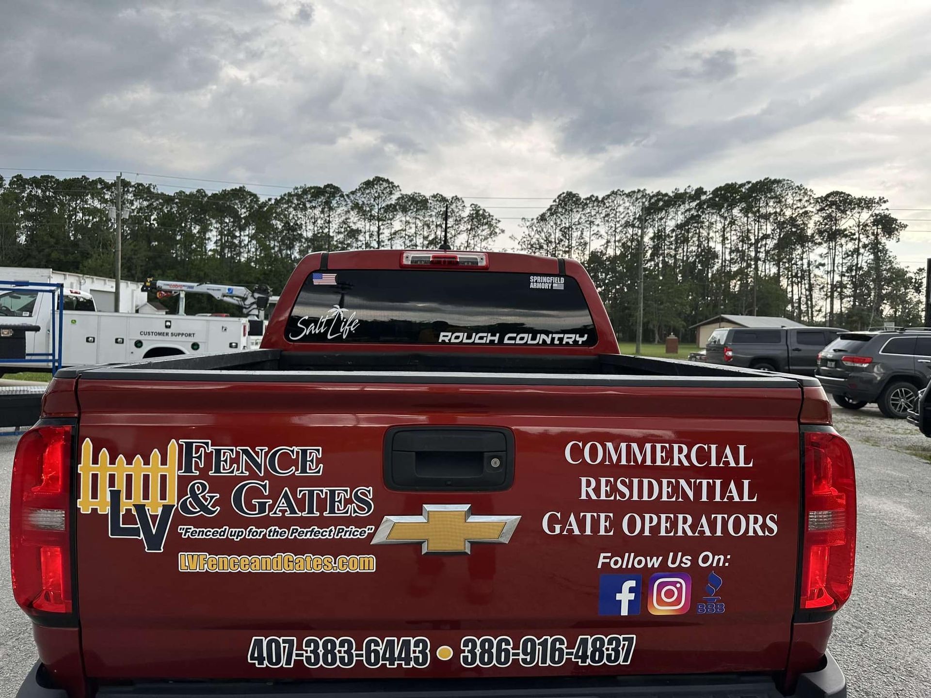 Red pickup truck with LV Fence & Gates logo on the tailgate. Text advertises commercial and residential gate operator services, with contact info.