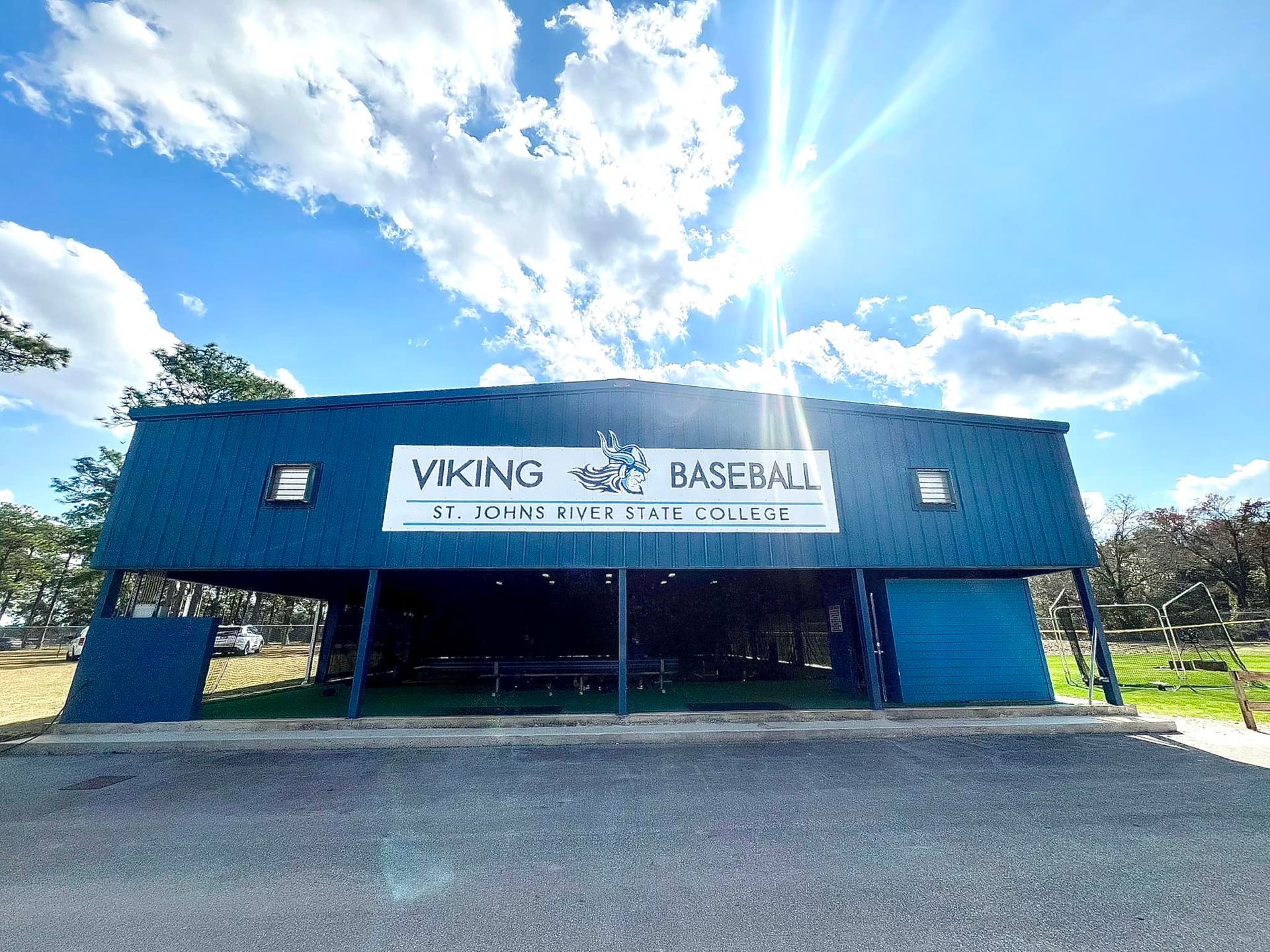 Blue dugout for Viking Baseball at St. John's School under a sunny sky with white clouds.