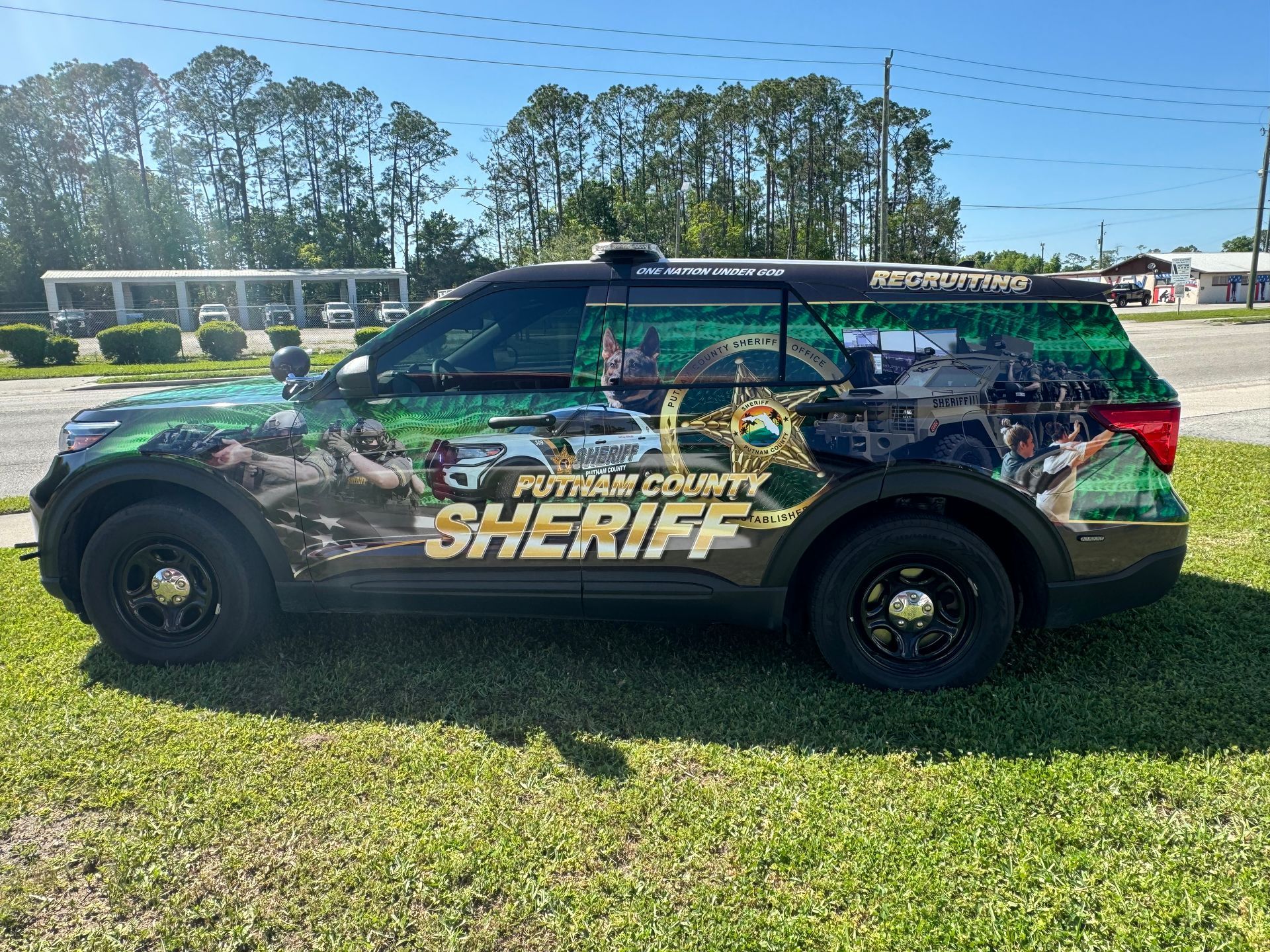 Putnam County Sheriff SUV parked on grass with a colorful wrap depicting scenes and the sheriff's office logo.