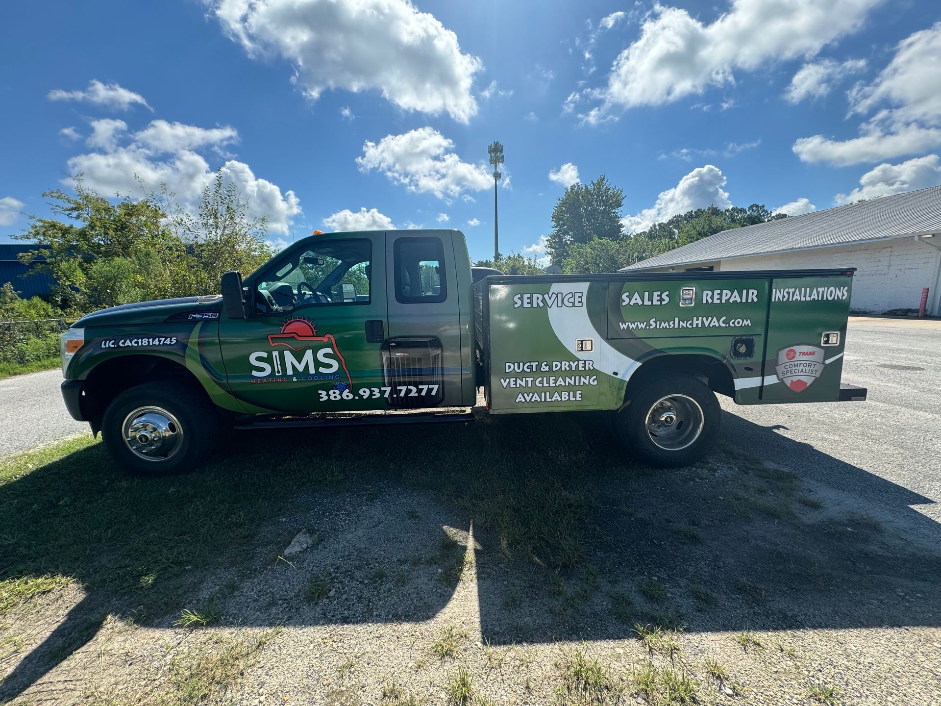 Green and gray company truck parked outside. The truck has the business name 
