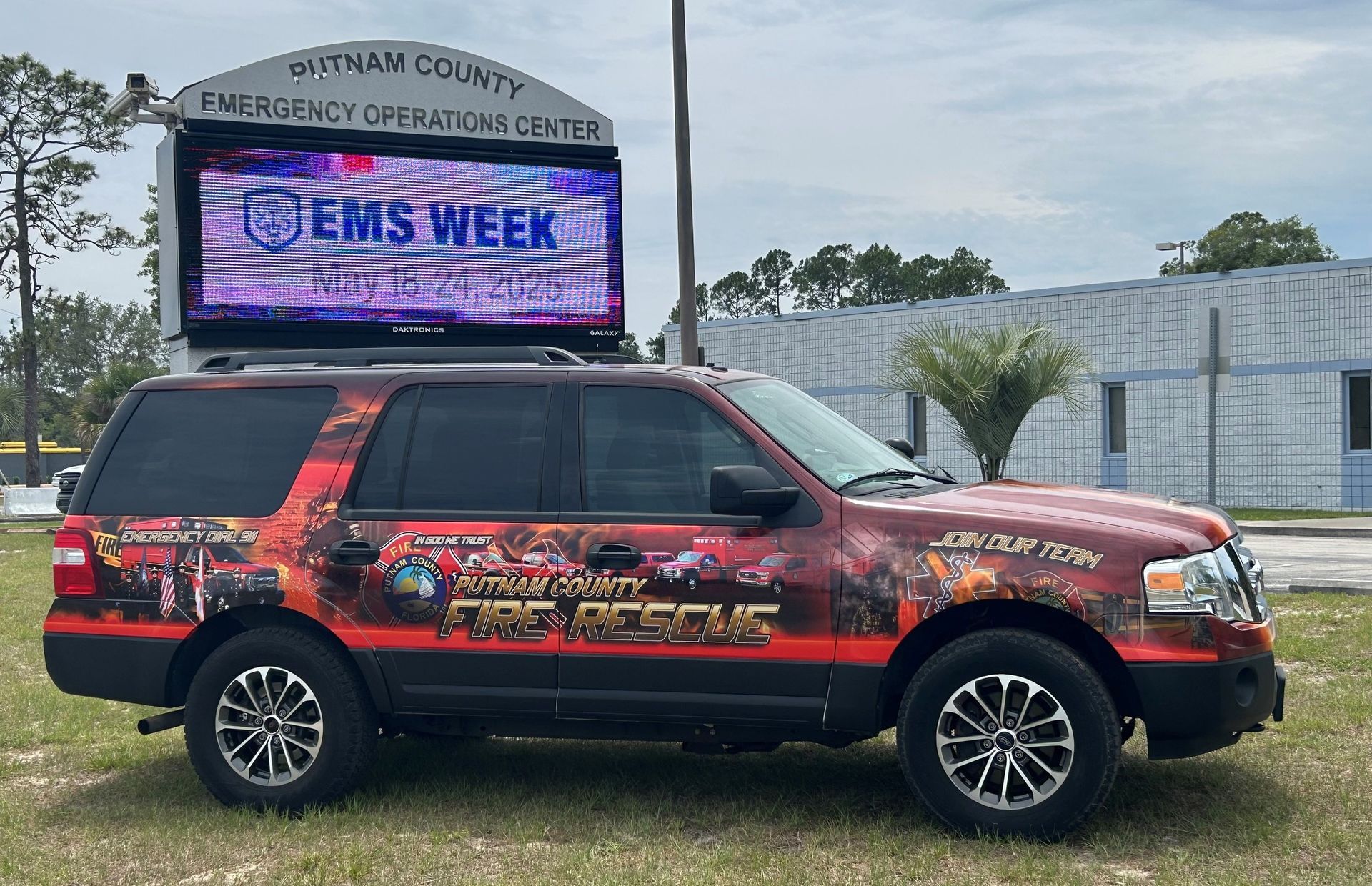 A red and black vehicle with a digital display on top promoting 