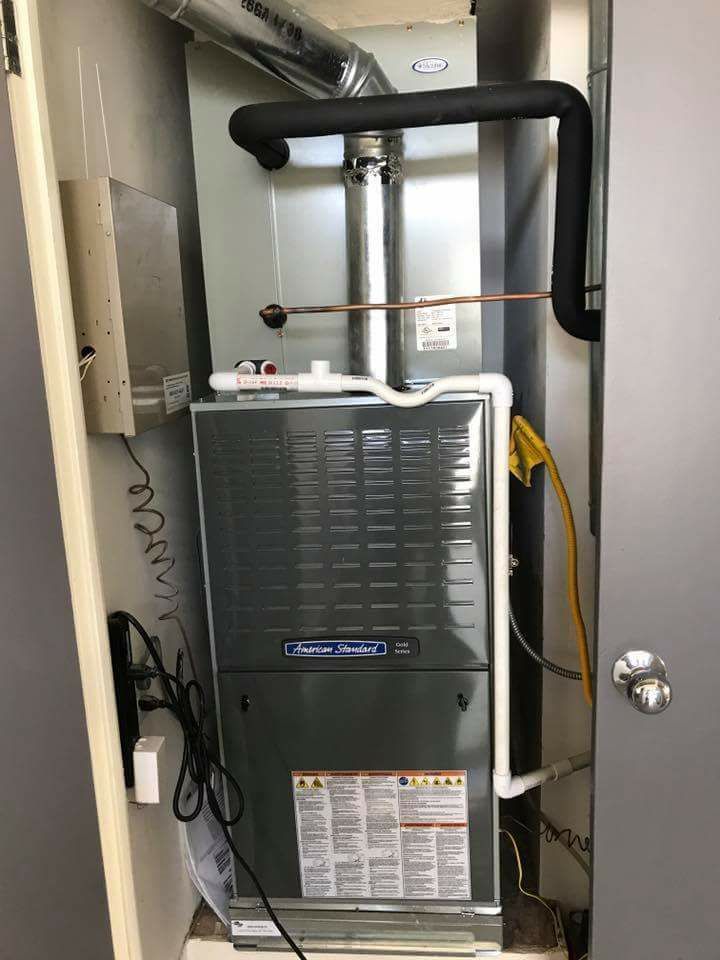 A furnace is sitting in a closet next to a door.