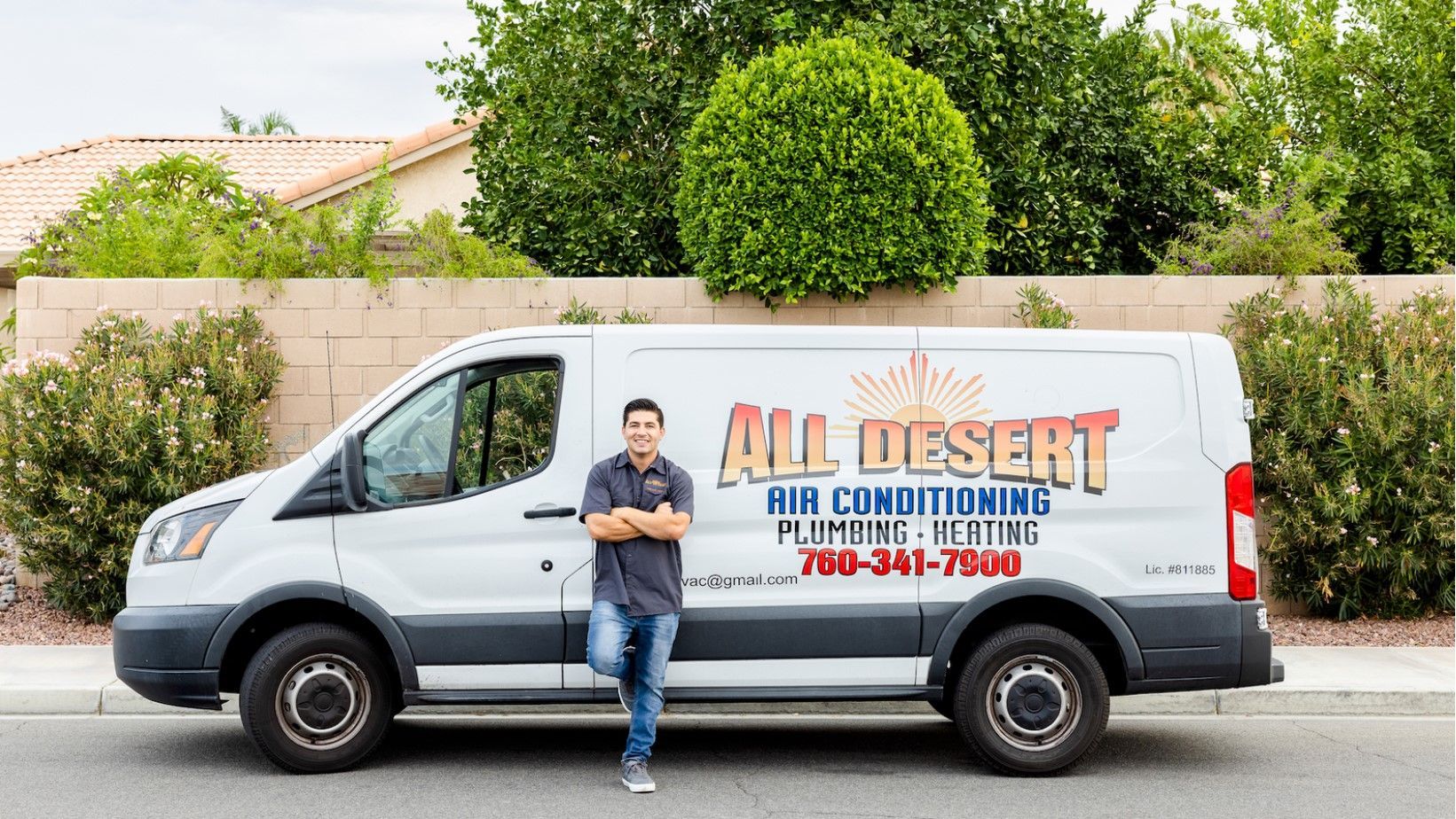 A man is standing next to a white van that says all desert air conditioning.