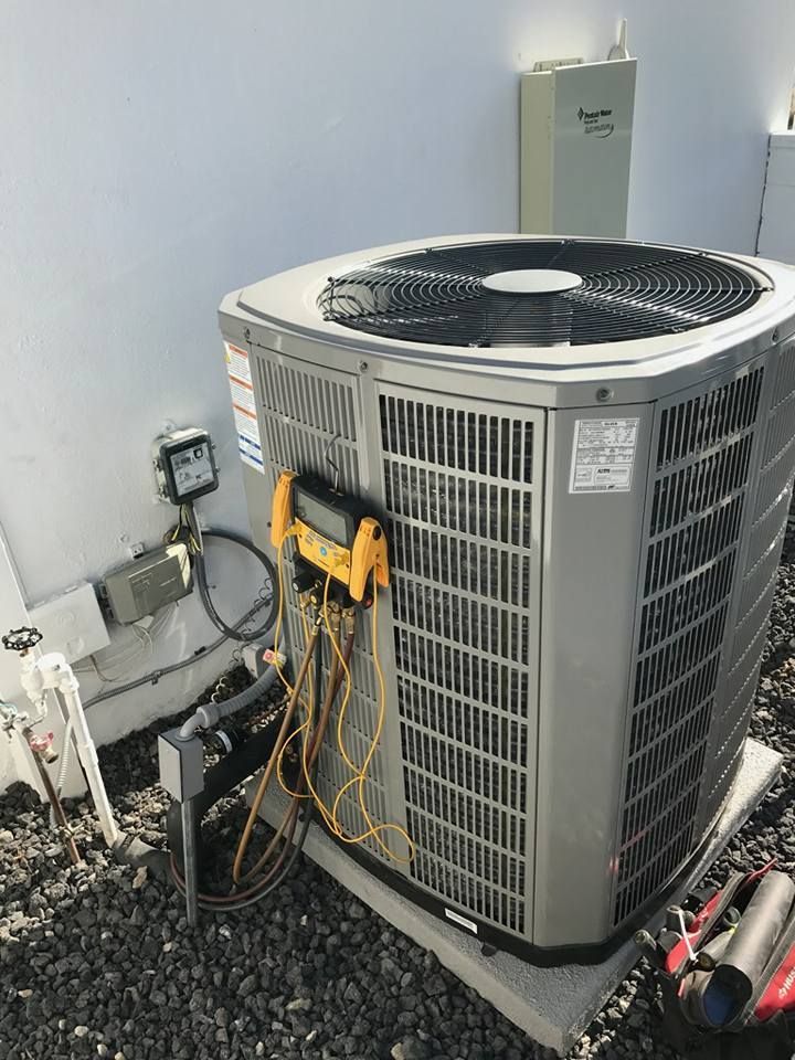 A large air conditioner is sitting on the ground next to a wall.