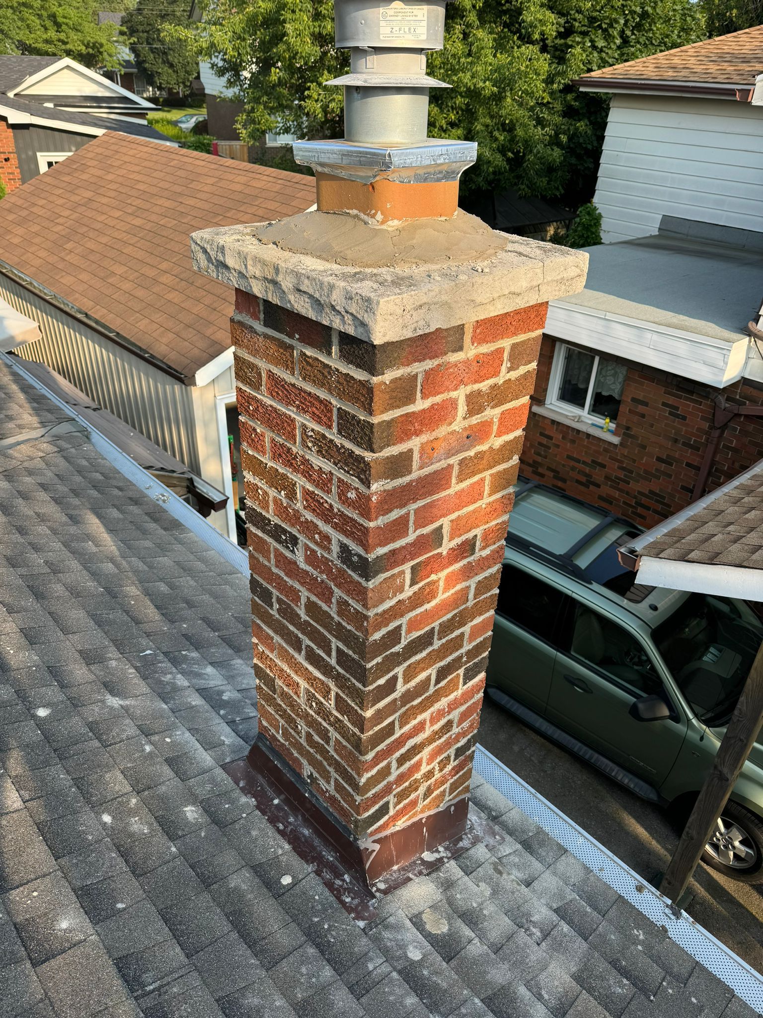 Man sandblasting a brick chimney on a roof under a blue sky, with wood supports.