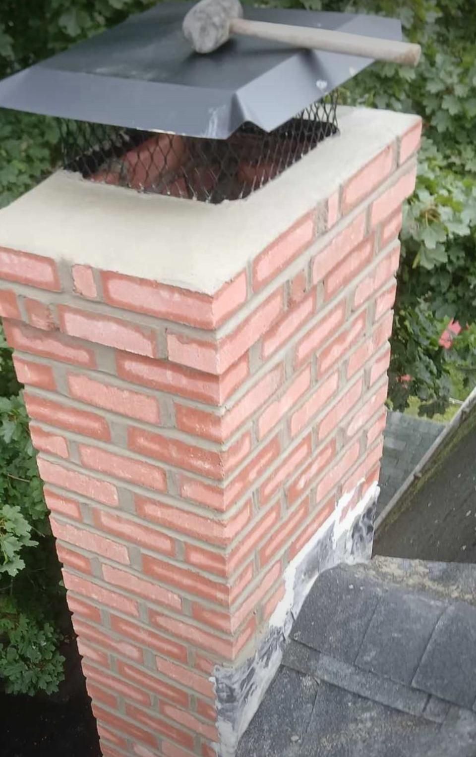 Brick chimney with a metal cap on a roof.