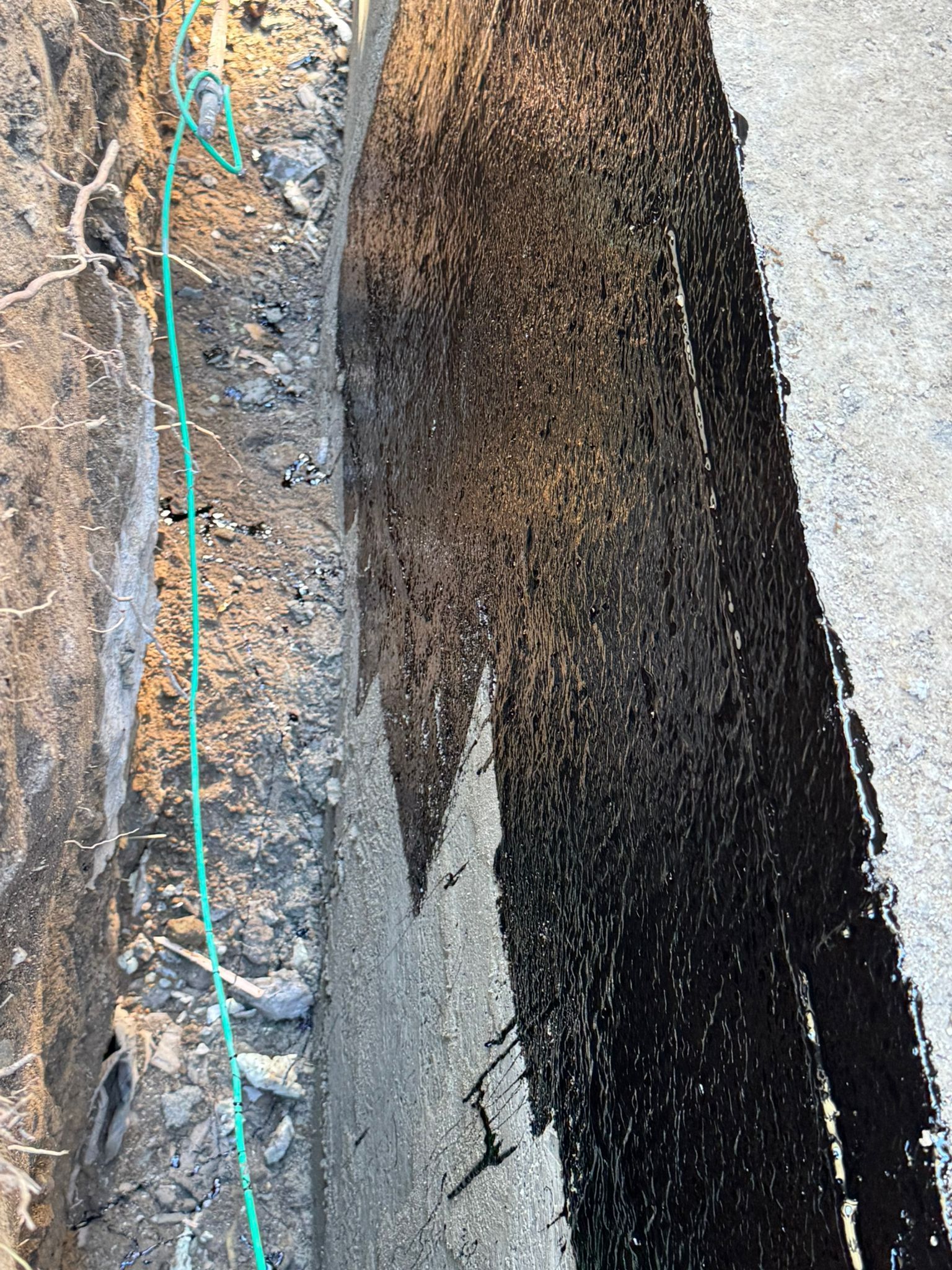 Dark trench with a green string and black coating applied to one side.