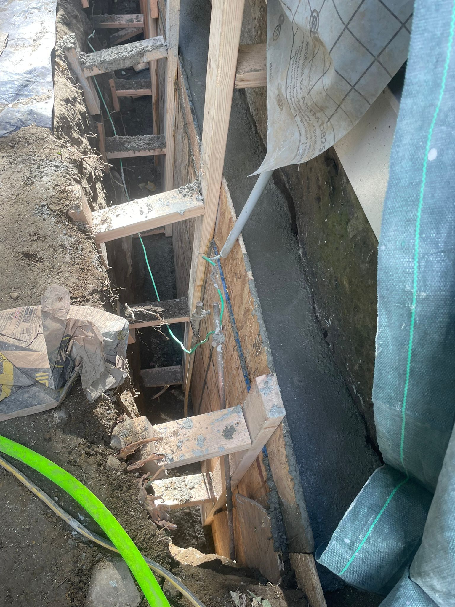 Wooden structure with dark fabric and green tubing. Construction site.