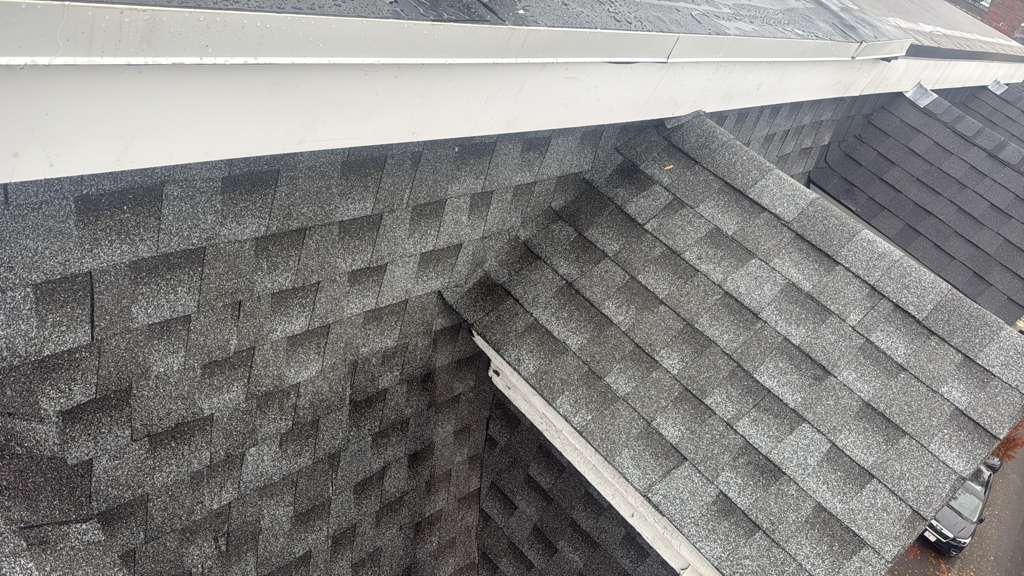 Dark gray asphalt shingle roof, close up showing texture and gutter.