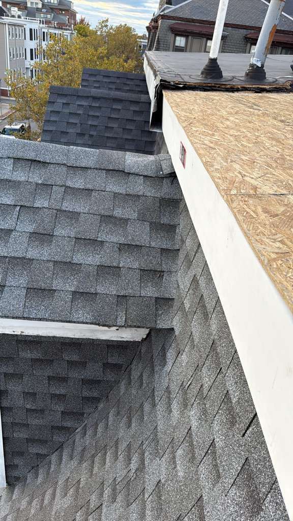 Three sections of a roof with varying shingle styles and a section of exposed plywood.