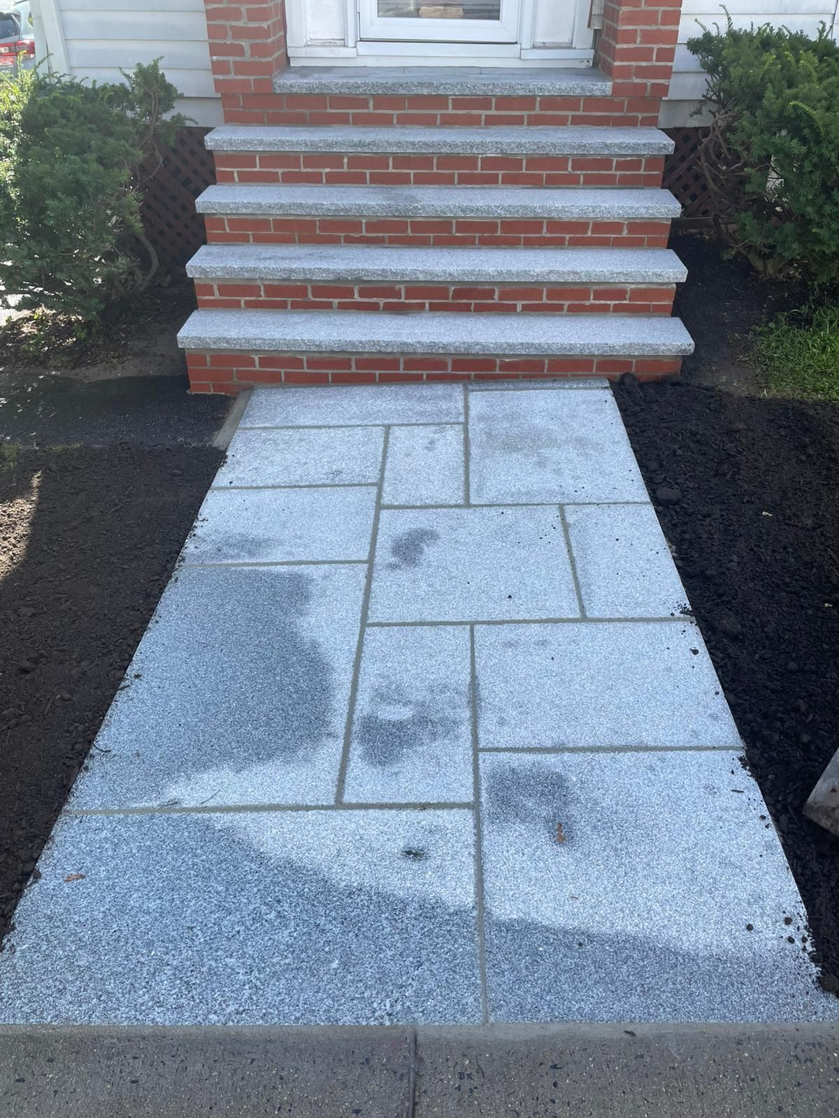 Stone walkway leading to brick steps and a white door.