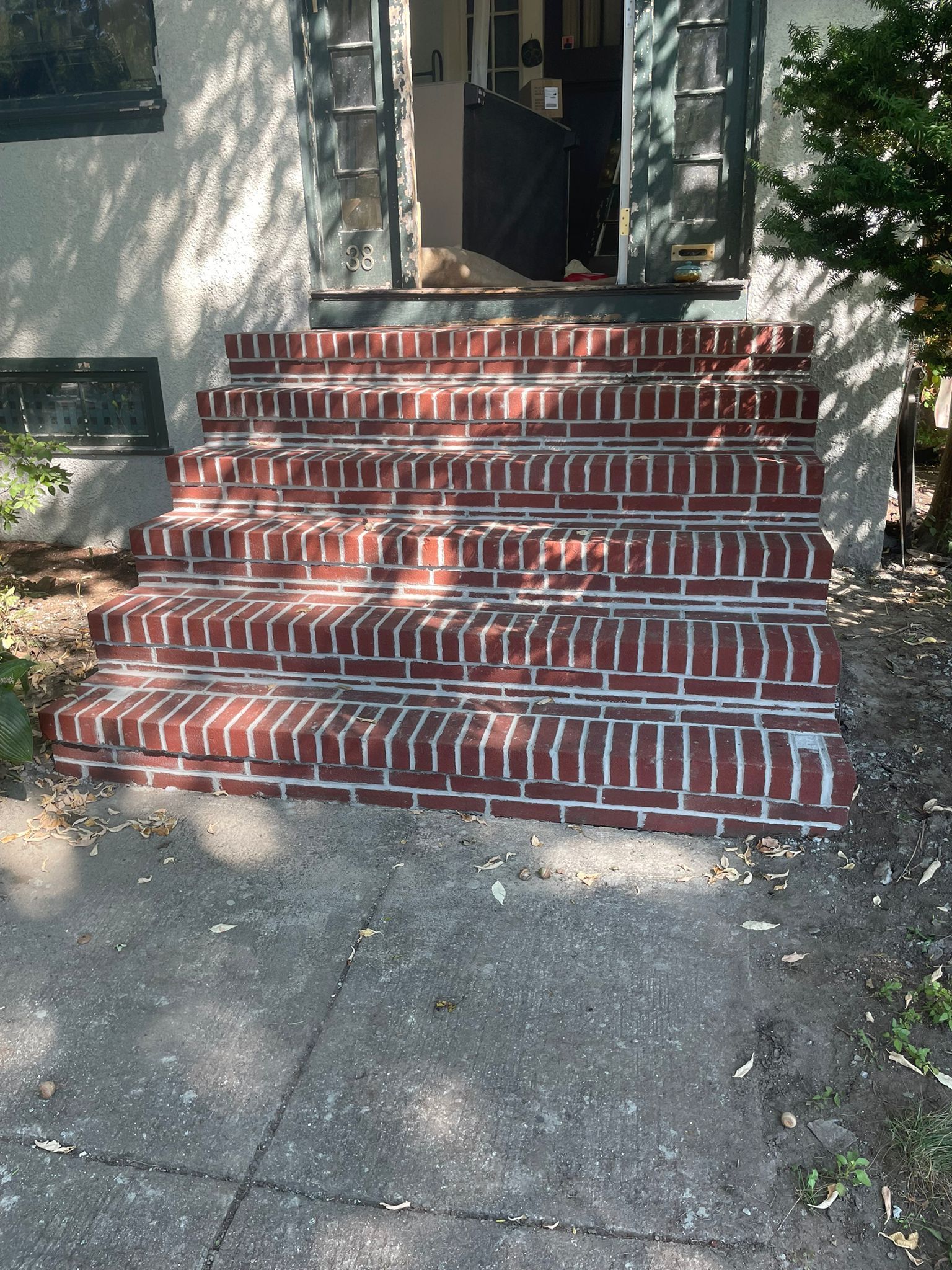 Brick steps leading to a doorway. Red bricks, white mortar, sunlight.