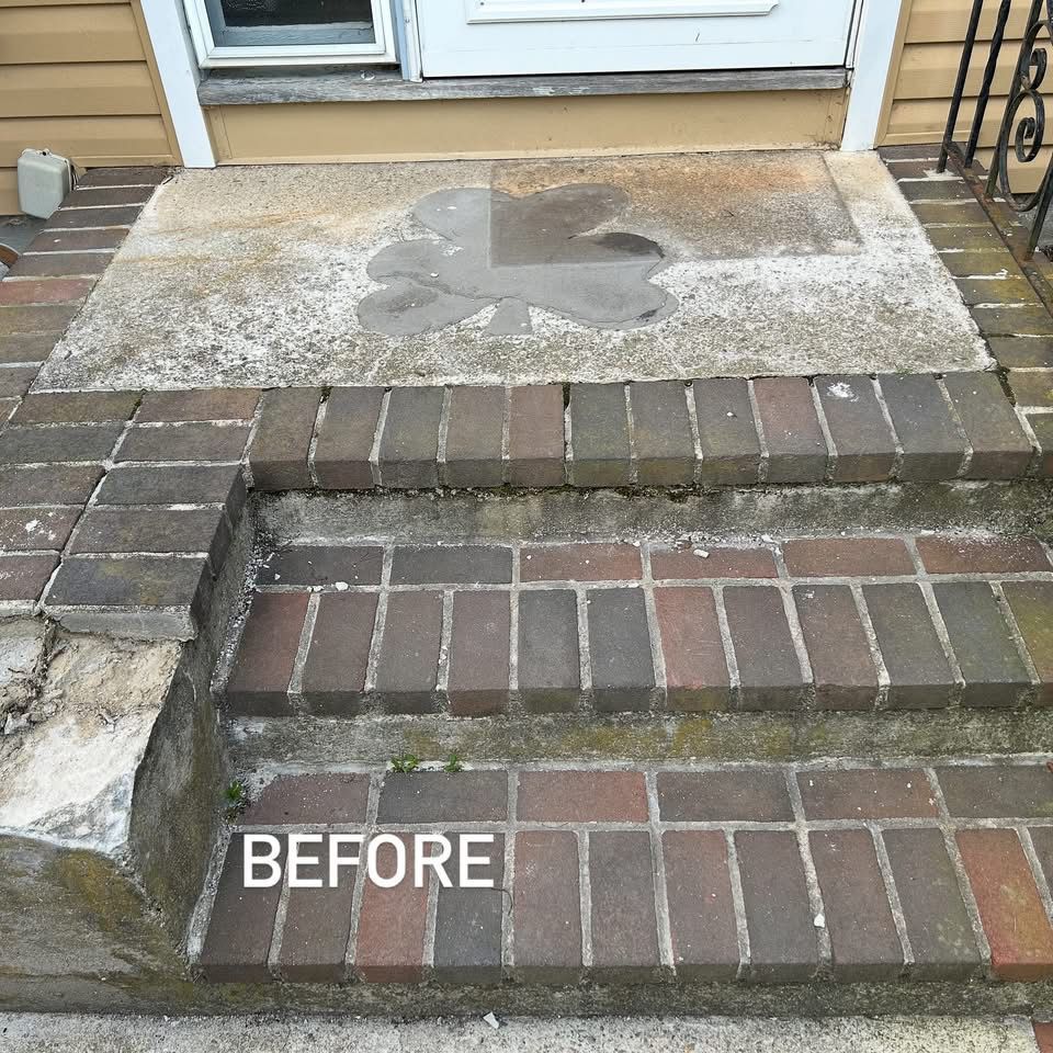 Brick steps leading up to a concrete landing with a doorway. 