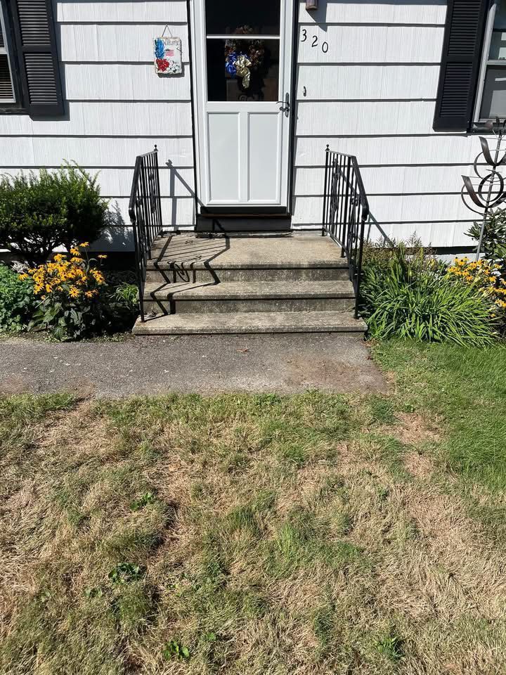 Exterior view: White house with steps leading to the front door. Black railings flank the steps.