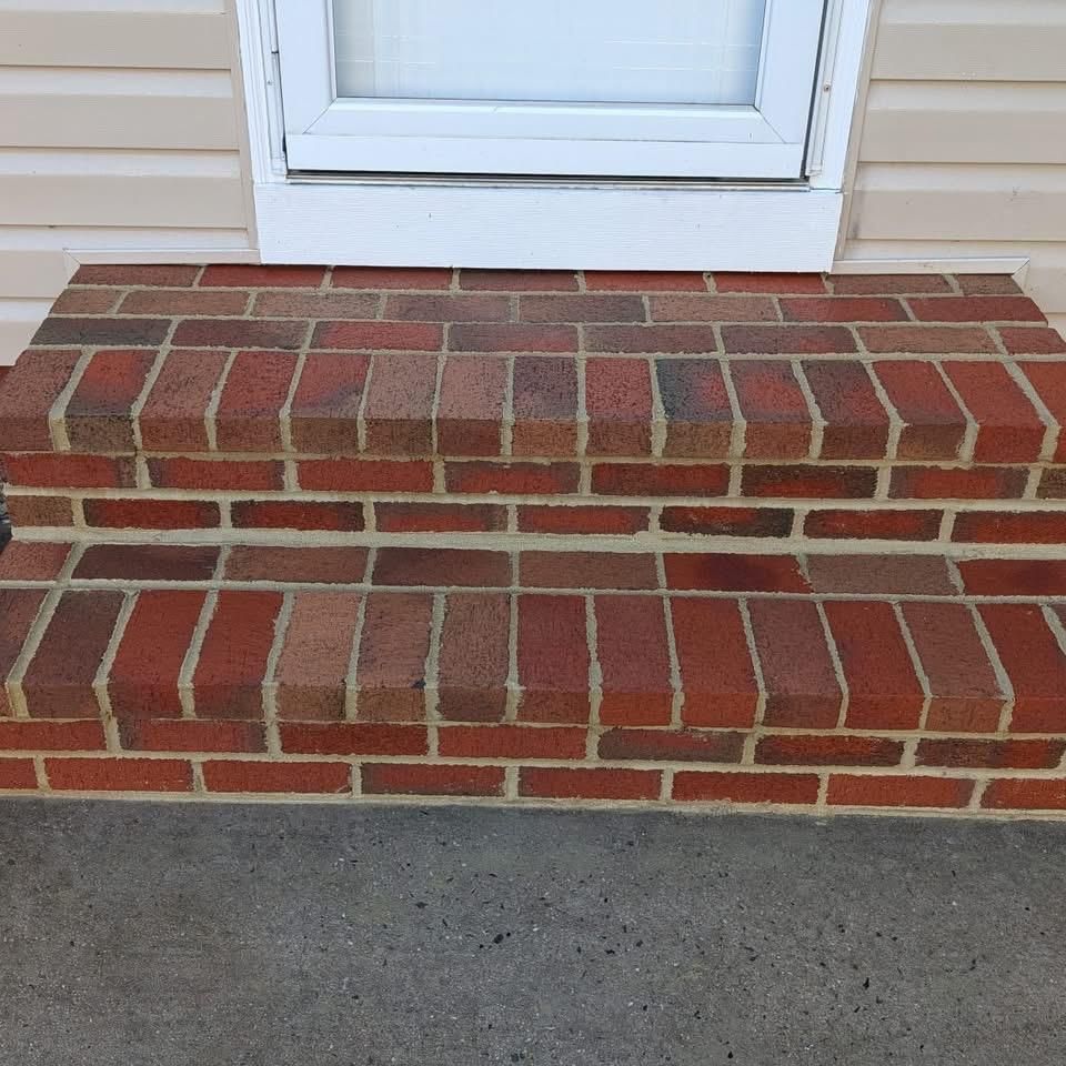 Brick steps leading to a white door, set against tan siding.