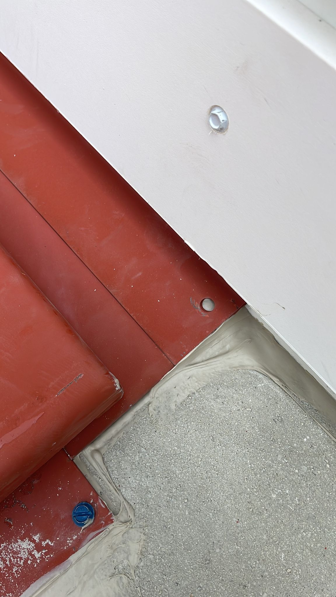 Red tile roof with a white trim and exposed hardware.