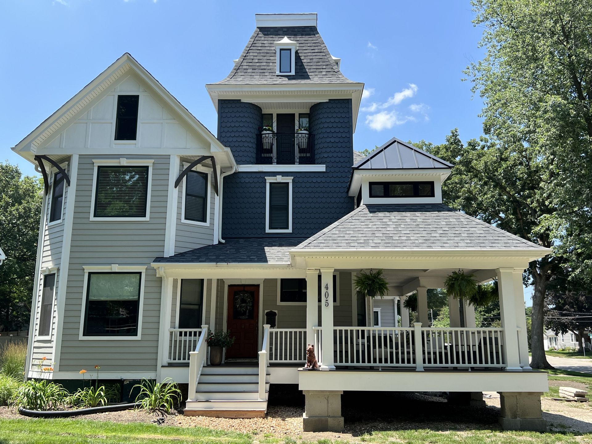 Victorian-style house with gray siding, white trim, porch, and blue sky
