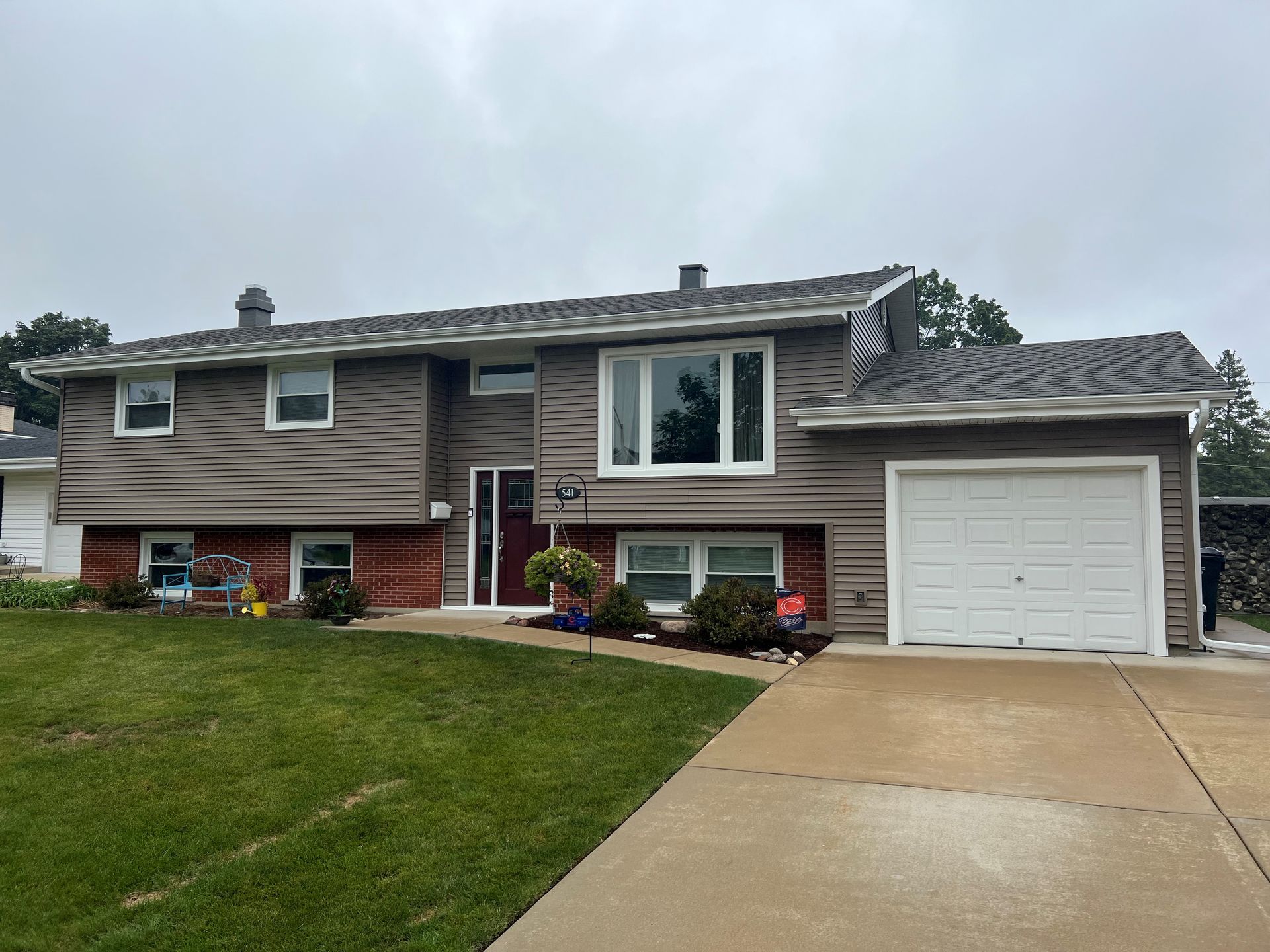 Suburban split-level house with a garage, driveway, and front lawn under cloudy skies