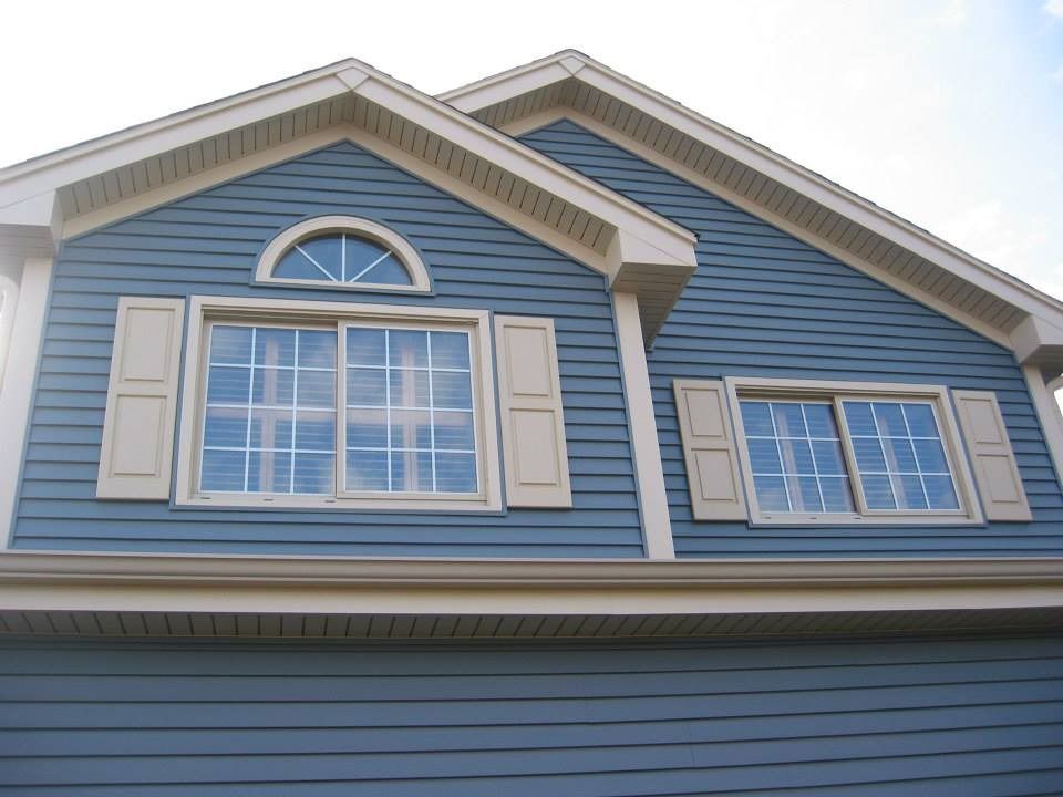 Blue house exterior with white-trimmed windows and shutters under a peaked roof