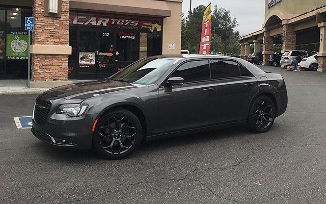 A chrysler 300 is parked in a parking lot in front of a store.