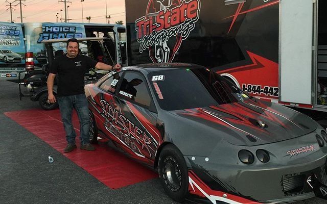 A man standing next to a race car that says the state